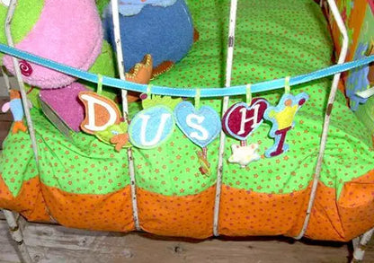 Stoffbuchstaben Alphabet als Dekoration an einem Kinderbett aufgehängt an einer kleinen Schnur in blau