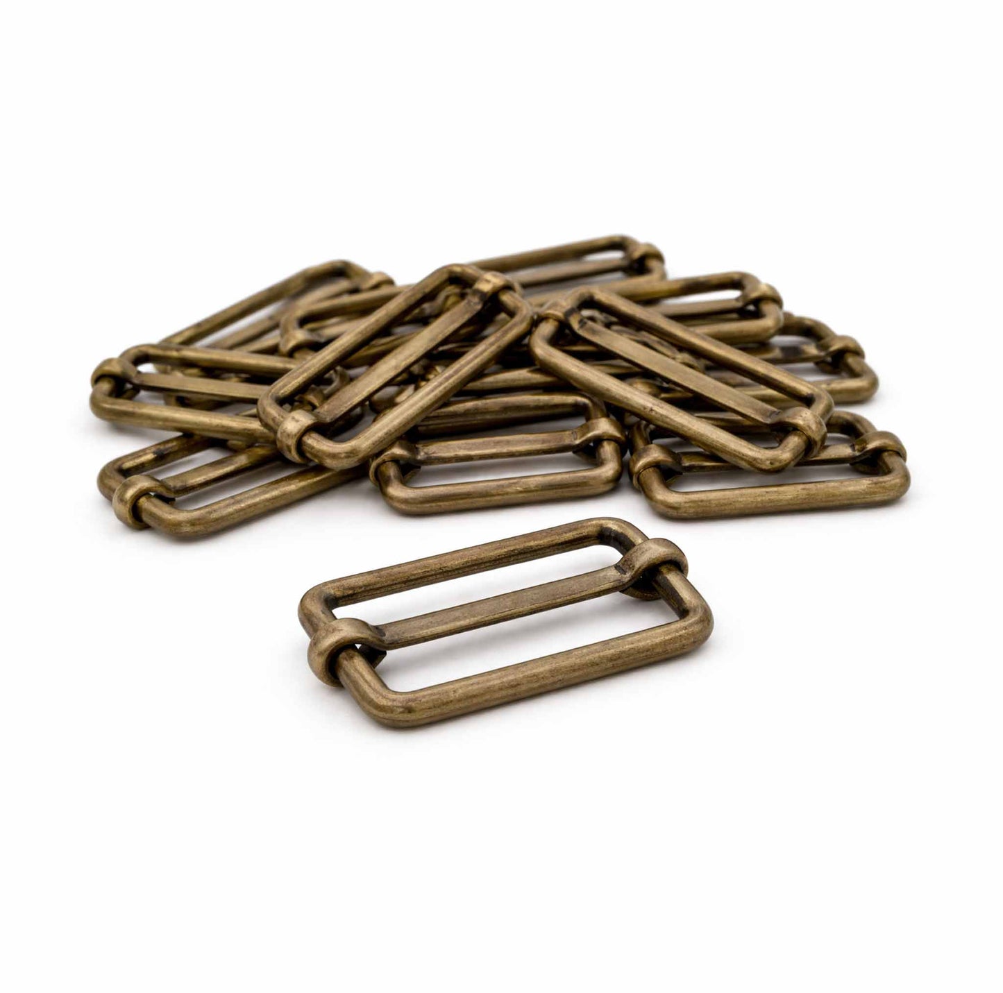 Leiterschnallen aus Metall in Altmessing als Haufen mit einer Schnalle im Vordergrund – 30 mm für Gurtband zur Taschenherstellung